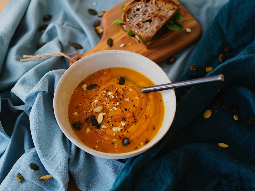 Eine Schale cremige Kürbissuppe mit herbstlicher Garnitur